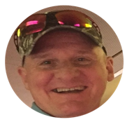 Smiling man wearing camouflage hat and reflective sunglasses indoors